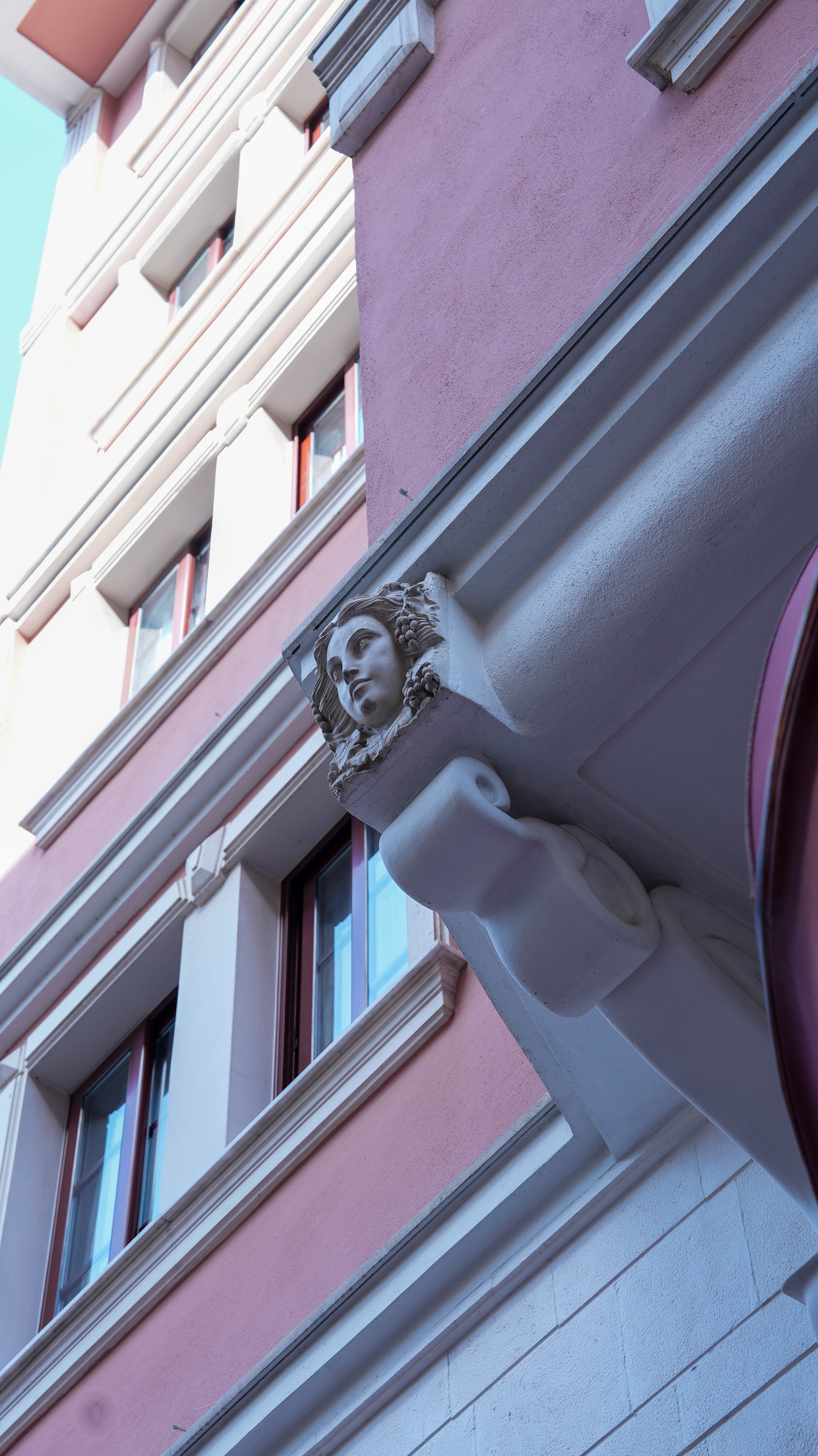 Park Hotel İzmir Low-angle view of a building facade with a decorative stone face sculpture under a ledge and several windows