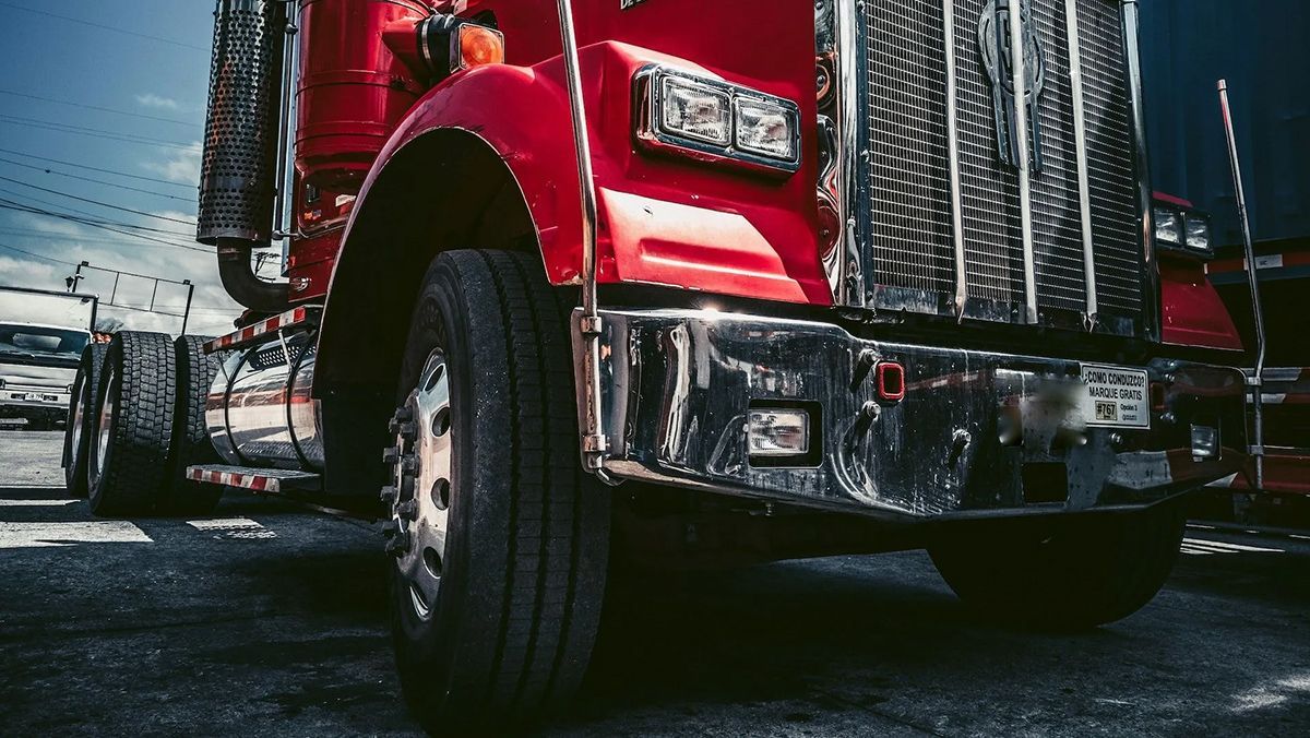 A red semi truck is parked on the side of the road.