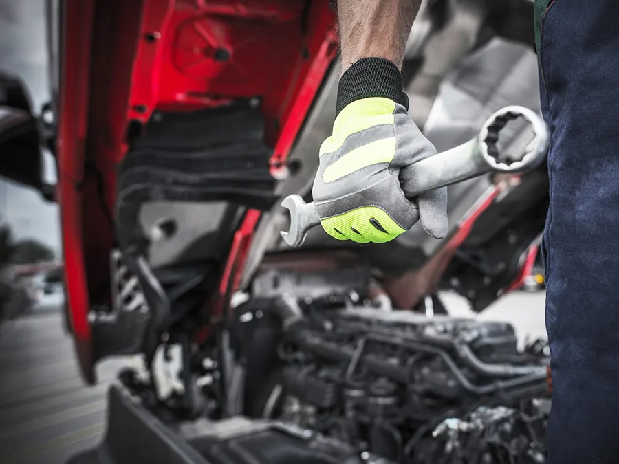 A man is working on a truck with a wrench in his hand.