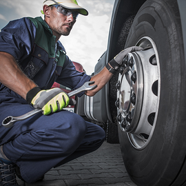 A man is working on a truck tire with a wrench
