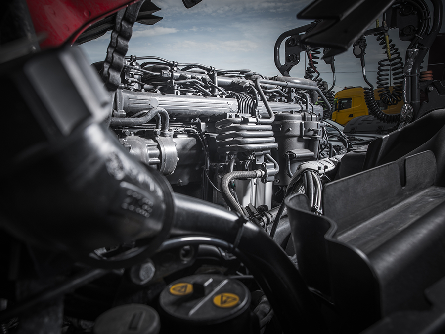 A close up of the engine of a truck with the hood open.