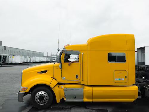 A yellow semi truck is parked in a parking lot.