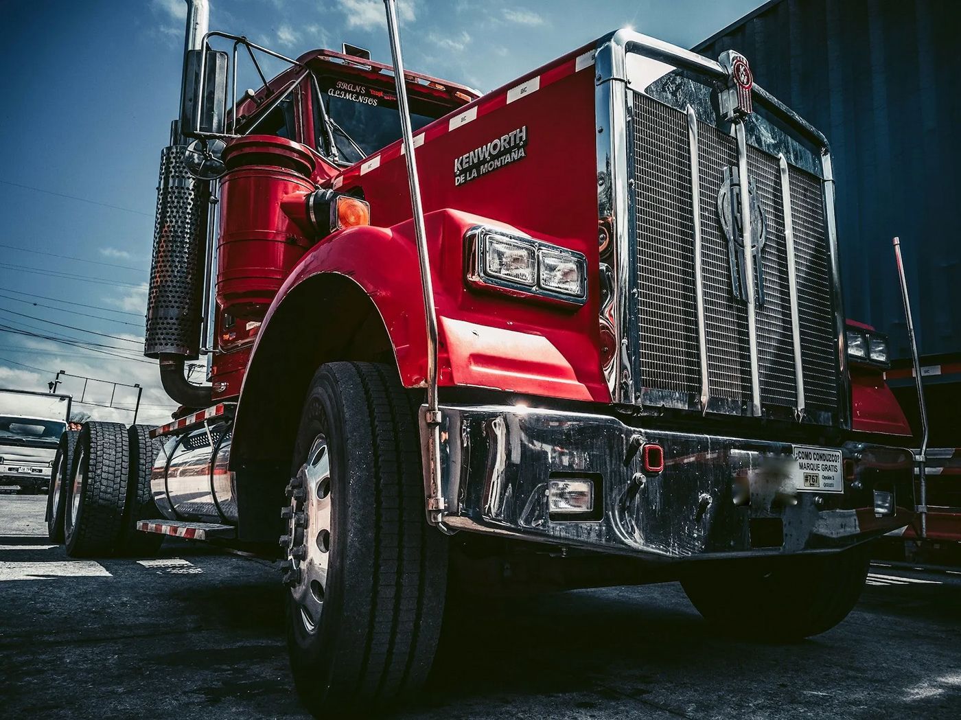Red Kenworth semi-truck, chrome accents, against a blue sky.