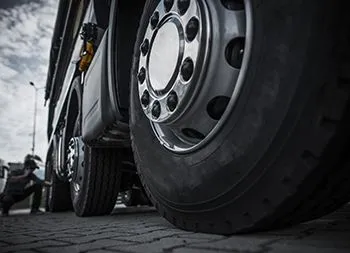 A close up of a truck wheel on a brick road.