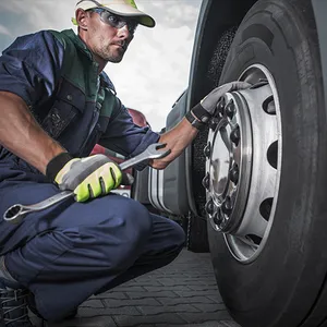 A man is working on a truck tire with a wrench.