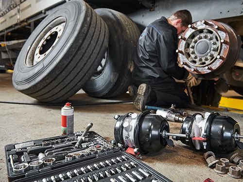 A man is working on a truck in a garage.