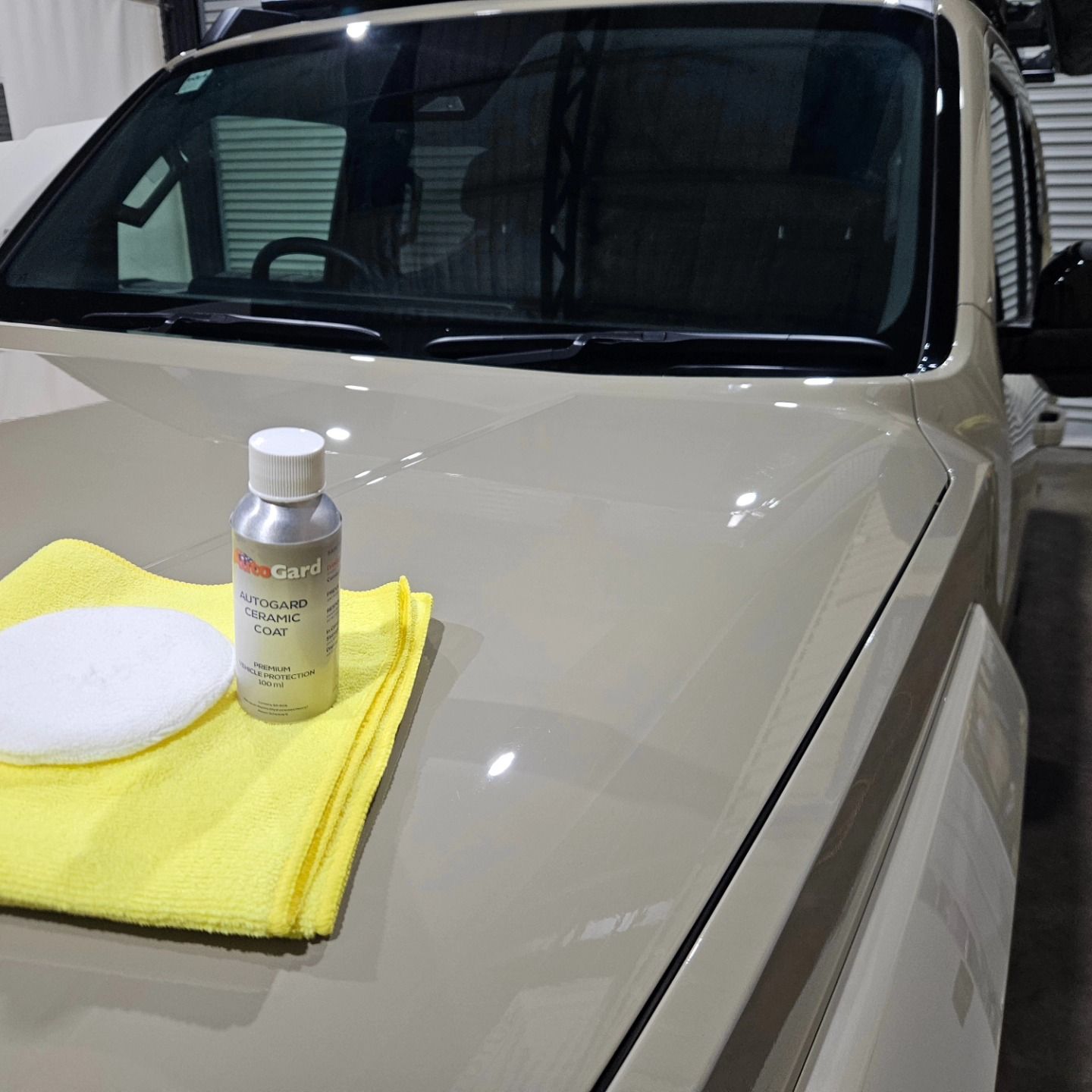 White car hood with a yellow microfiber towel, white applicator pad, and detailing bottle on top — On Point Detailing Wagga in East Wagga Wagga, NSW