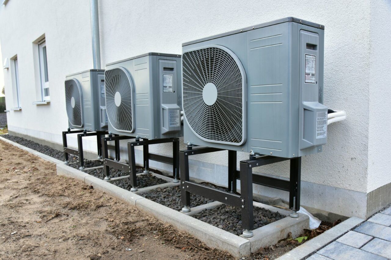 Three Gray Heat Pump Units Mounted Outside a Building — Hinterland Air Conditioning Sunshine Coast in Kiels Mountain, QLD