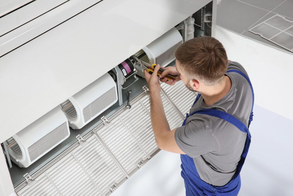 A Technician in Repairs an Air Conditioning Unit — Hinterland Air Conditioning Sunshine Coast in Buderim, QLD