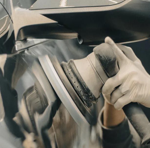 Close-up of a person polishing a car with a circular buffing tool.