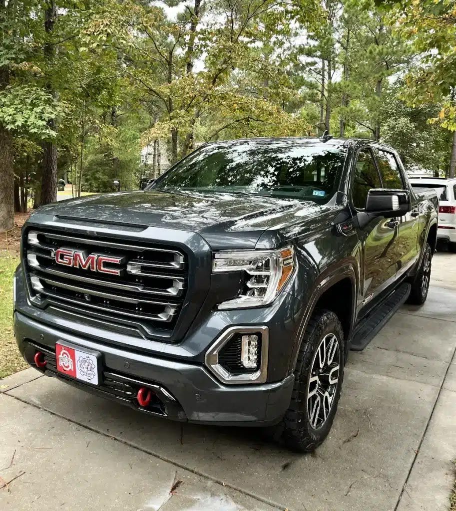 Dark gray GMC pickup truck parked on a driveway under trees