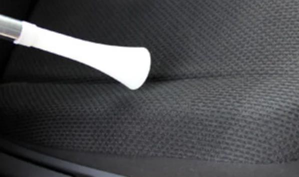 A white wand-like object resting on a dark textured surface