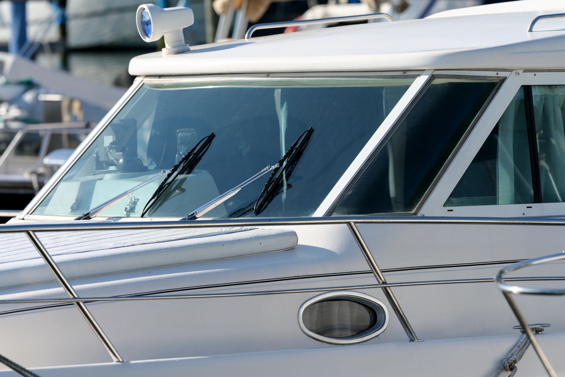 White yacht cockpit with windshield wipers and chrome railing on the water
