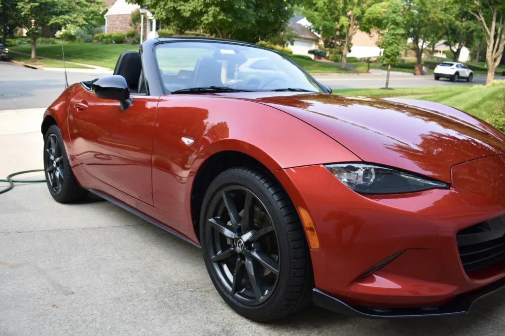 Red convertible sports car parked in a driveway, viewed from the front-left side.