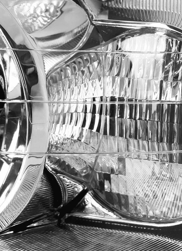 Close-up of a chrome car headlight with ribbed glass and reflective detailing