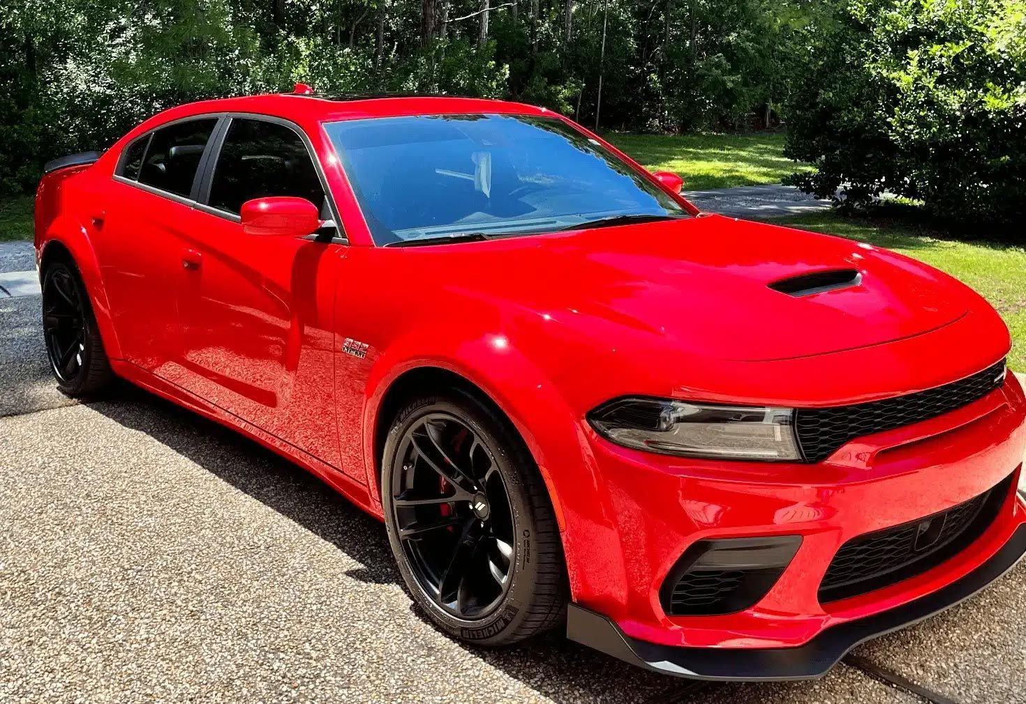 Red sports car parked on a driveway with trees in the background
