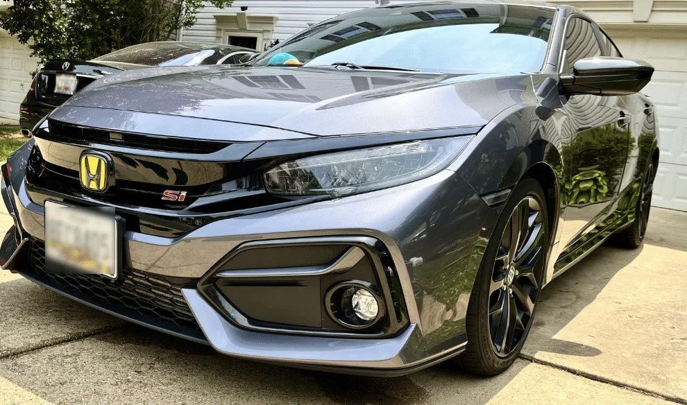Gray Honda sedan parked in a driveway, front-left view with black wheels and sunlight reflection