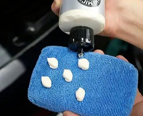 Toothpaste dots on blue cloth held under a toothpaste tube nozzle