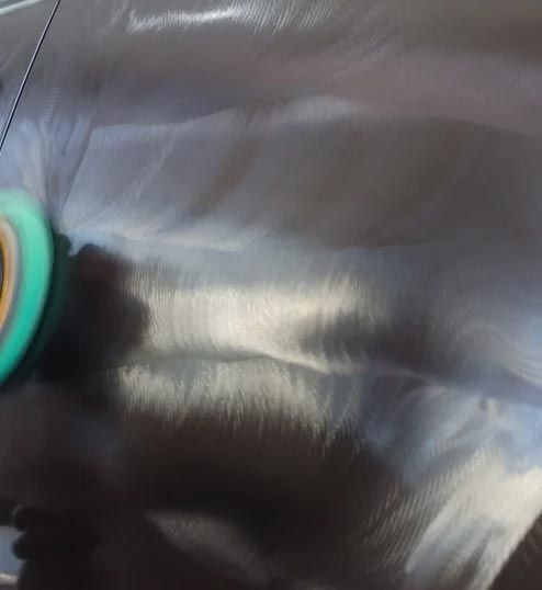 Close-up of a glossy black leather surface with a teal and orange object at the left edge