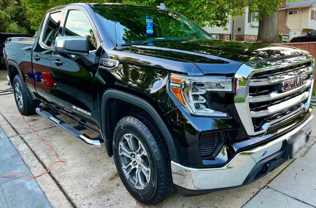 Black GMC pickup truck parked on a city street, front-left view