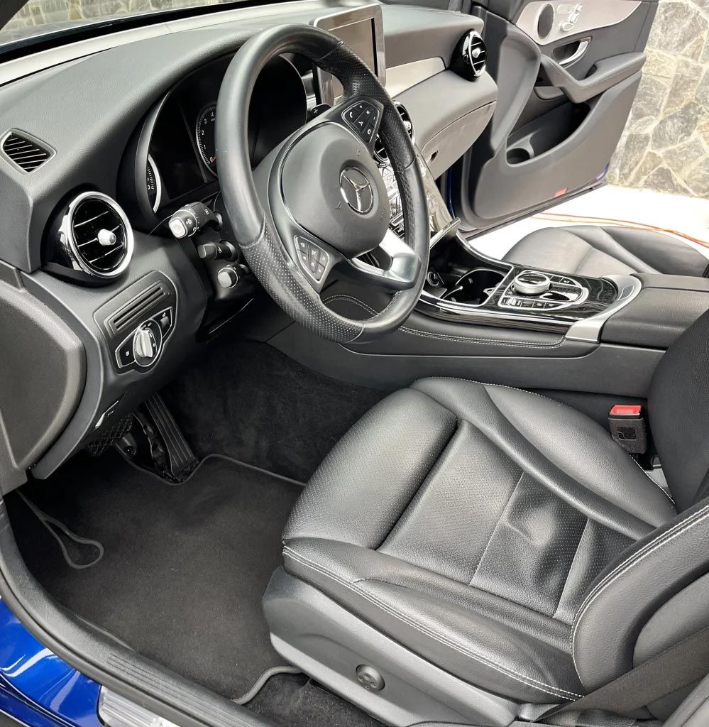 Interior of a black Audi with leather seats, dashboard, steering wheel, and open driver’s door.