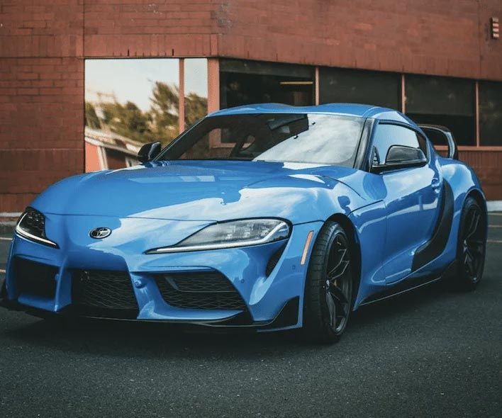 Blue sports car parked on a street beside a brick building