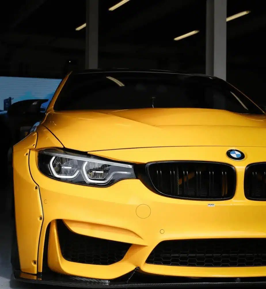 Yellow BMW sports car front view in a dim showroom