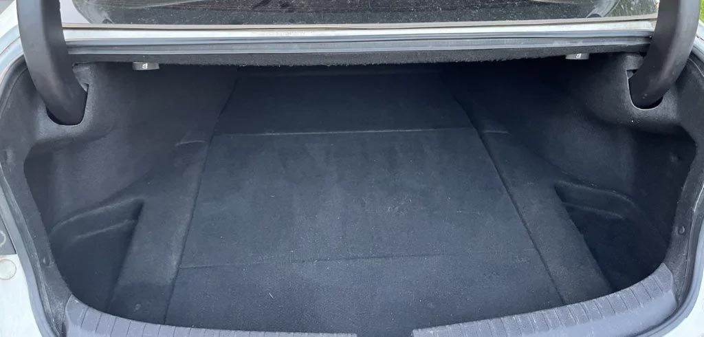 Empty car trunk with dark gray carpeted floor and folded rear seats visible
