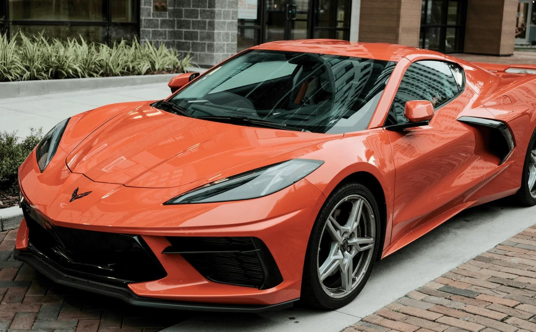 Orange sports car parked on a brick street in front of a building