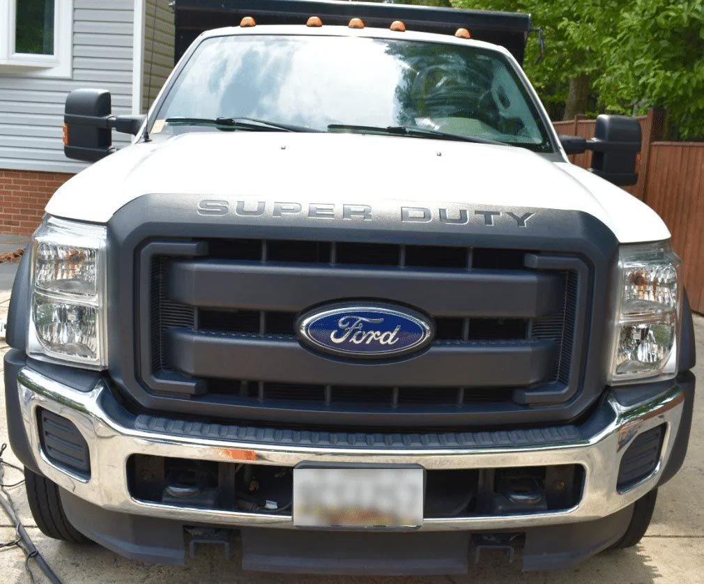 Front view of a white Ford Super Duty pickup truck with a chrome bumper parked outdoors.