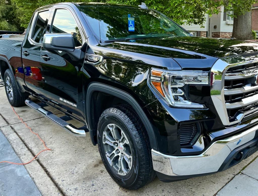 Black pickup truck parked by a curb, angled front view with chrome grille and step rails.
