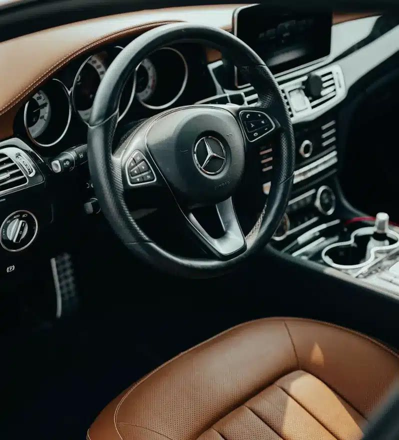 Mercedes-Benz car interior with black dashboard, steering wheel, and tan leather seats