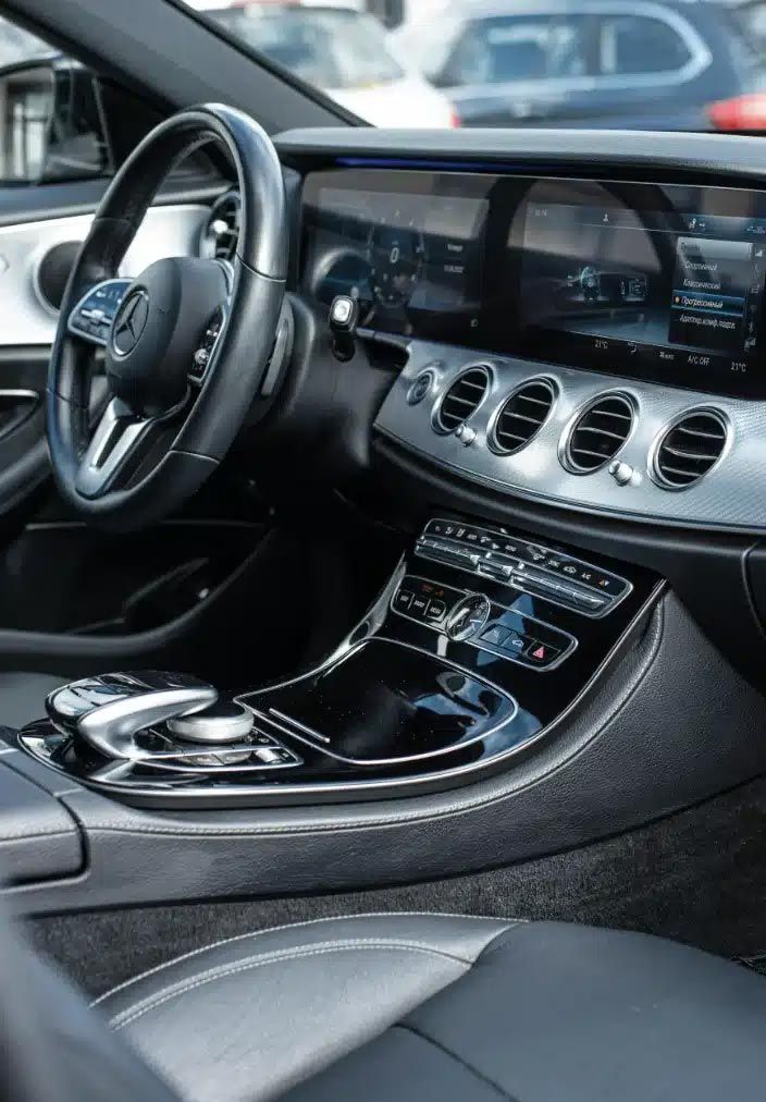 Luxury car interior with black leather seats, silver dashboard vents, and center console controls