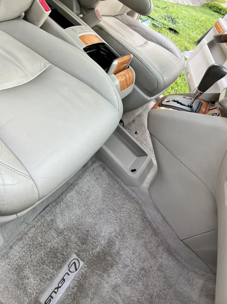 Gray car interior with front seats, center console, and a floor mat reading “LEXUS”