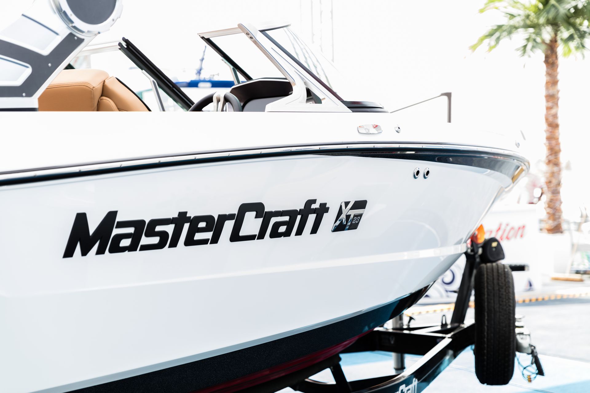 White MasterCraft boat on a trailer indoors, side view of the bow and logo
