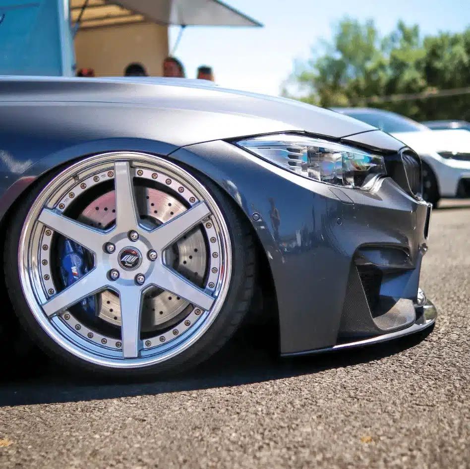 Lowered gray sports car with custom chrome wheel parked on pavement