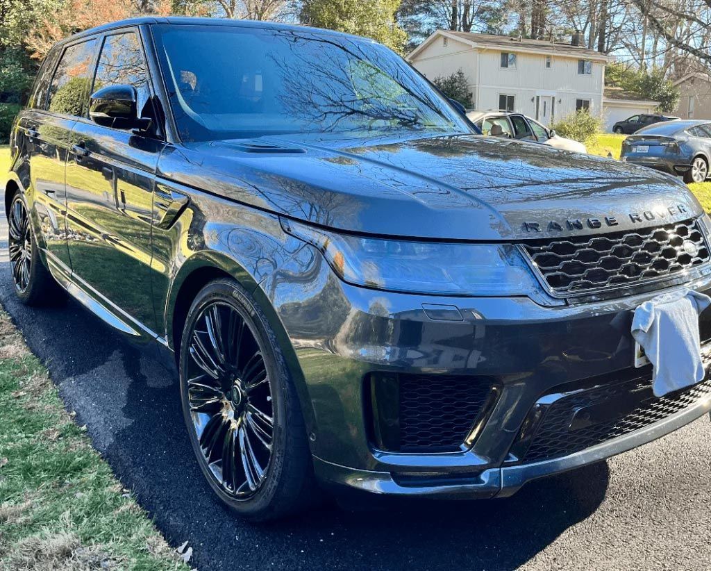 Gray Range Rover SUV parked outdoors on a sunny street, front-left view.