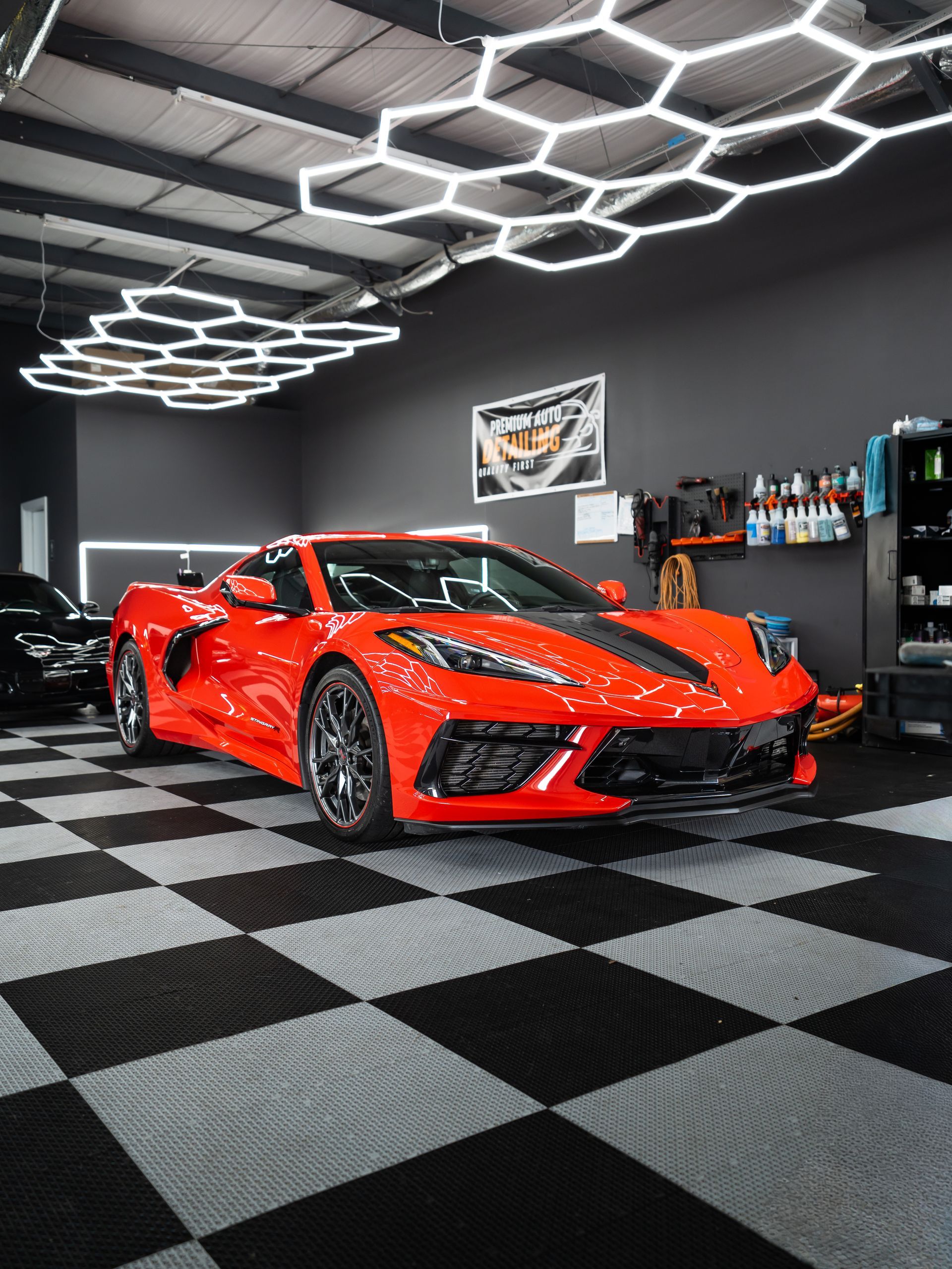 Red sports car in a modern showroom with hexagon ceiling lights and black-and-gray checkered floor