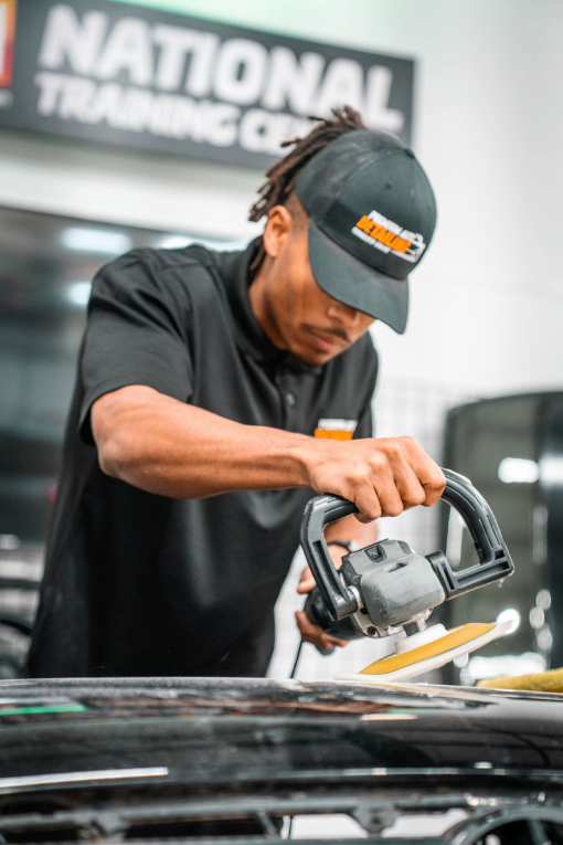 Mechanic using a buffer on a car in a National Tire & Battery shop