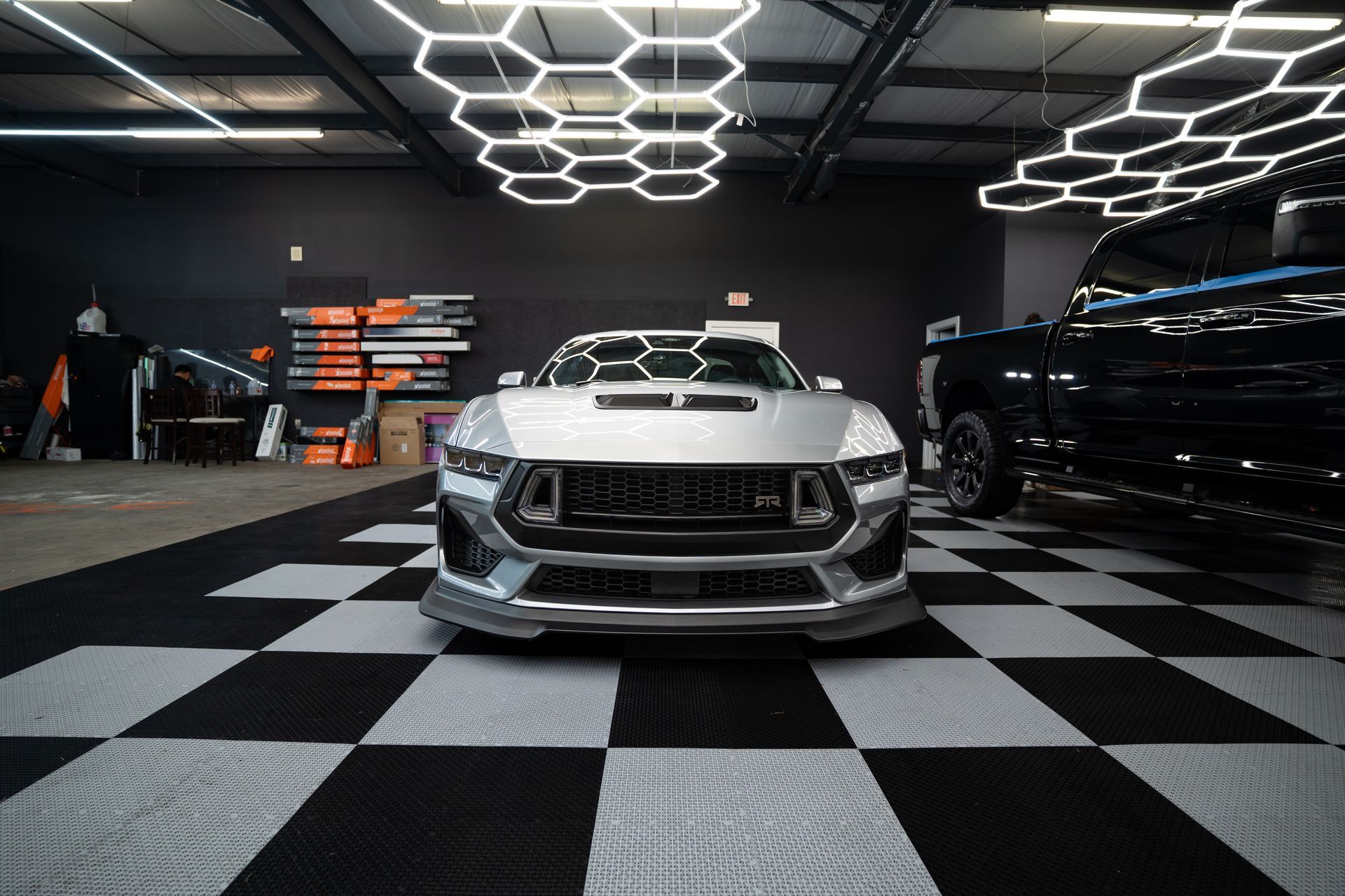 Silver sports car in a showroom with checkered floor and geometric ceiling lights