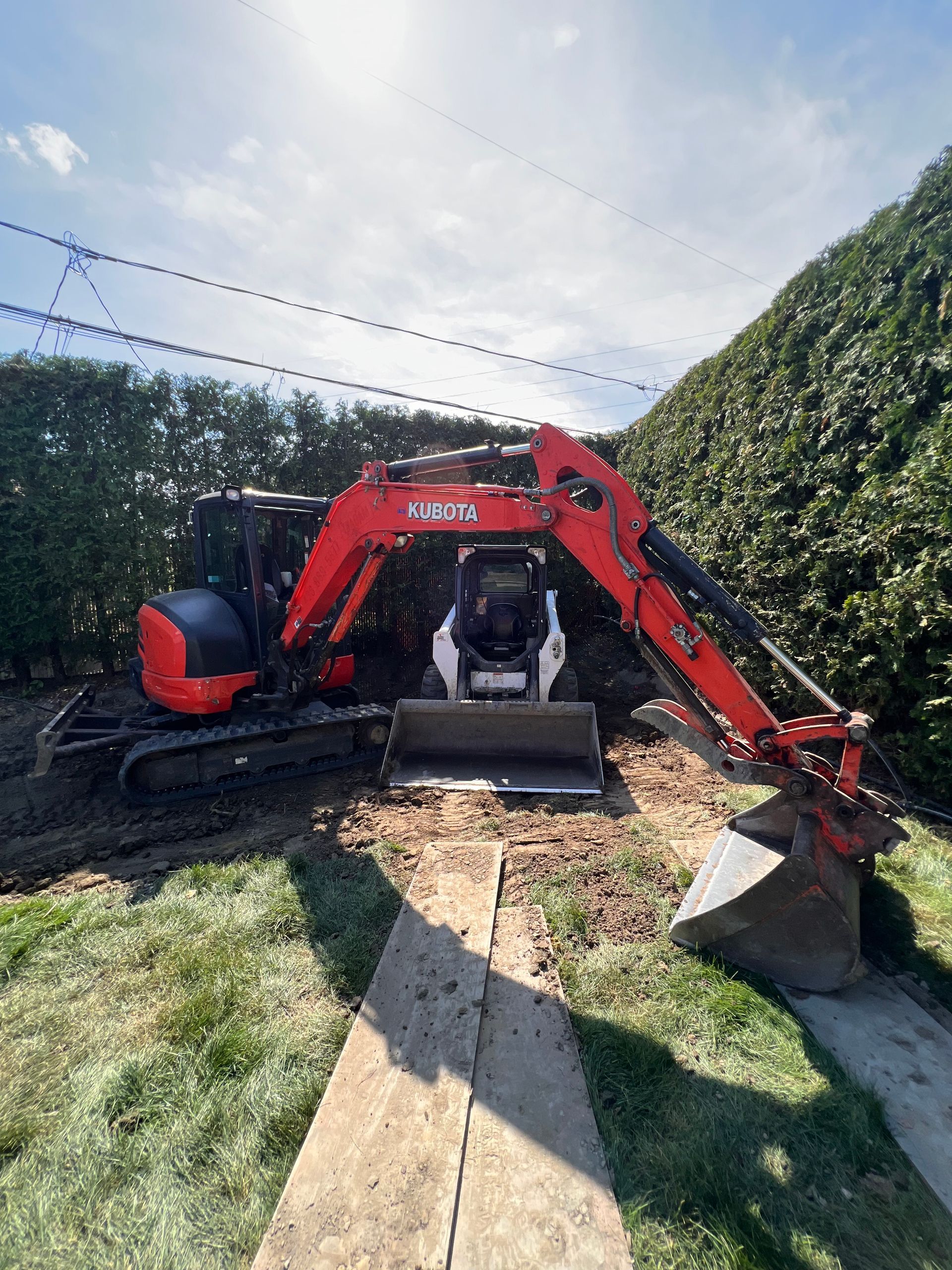 Une excavatrice rouge et noire est assise au sommet d'un champ couvert d'herbe.