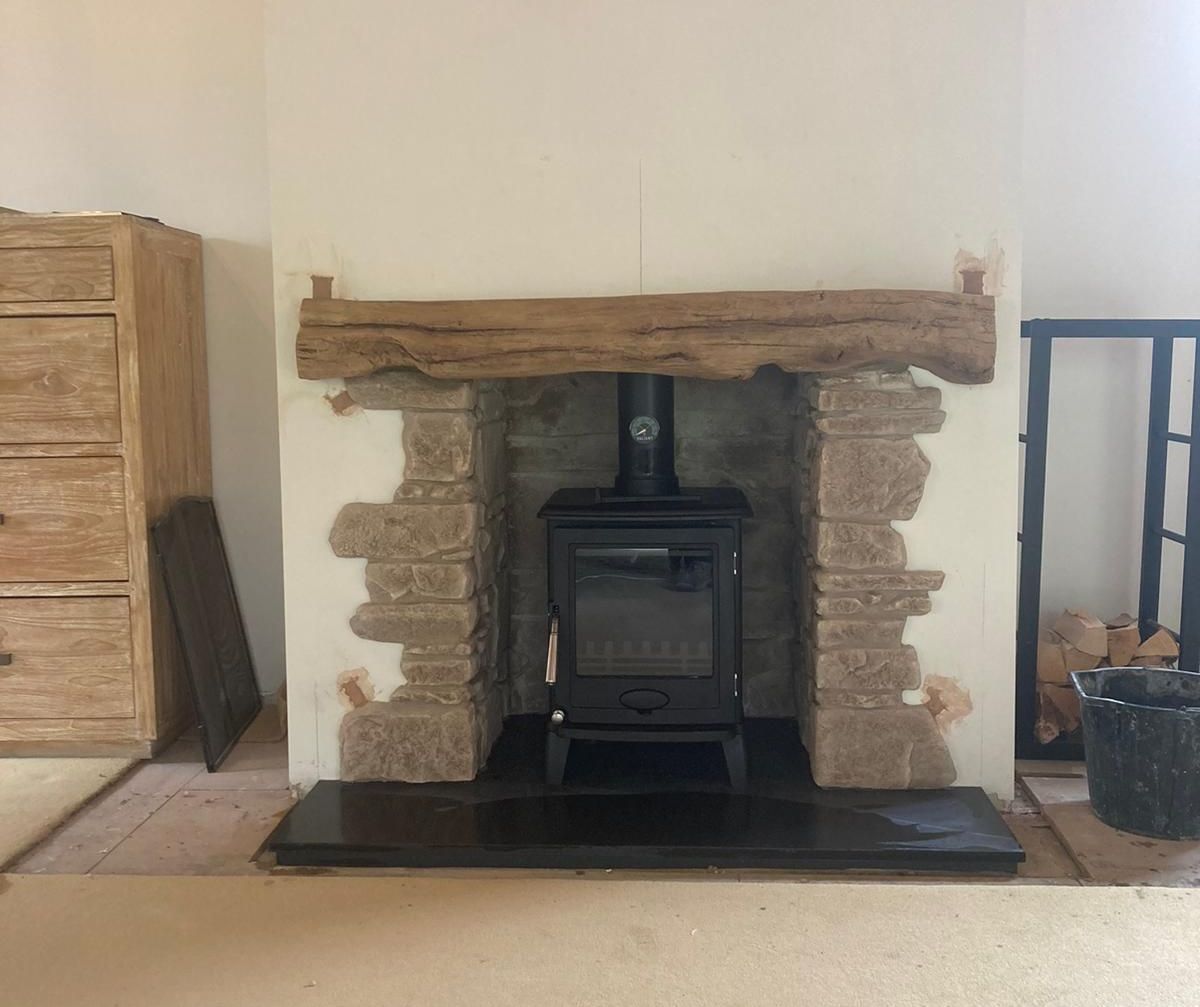 Wood burning stove in a rustic stone fireplace