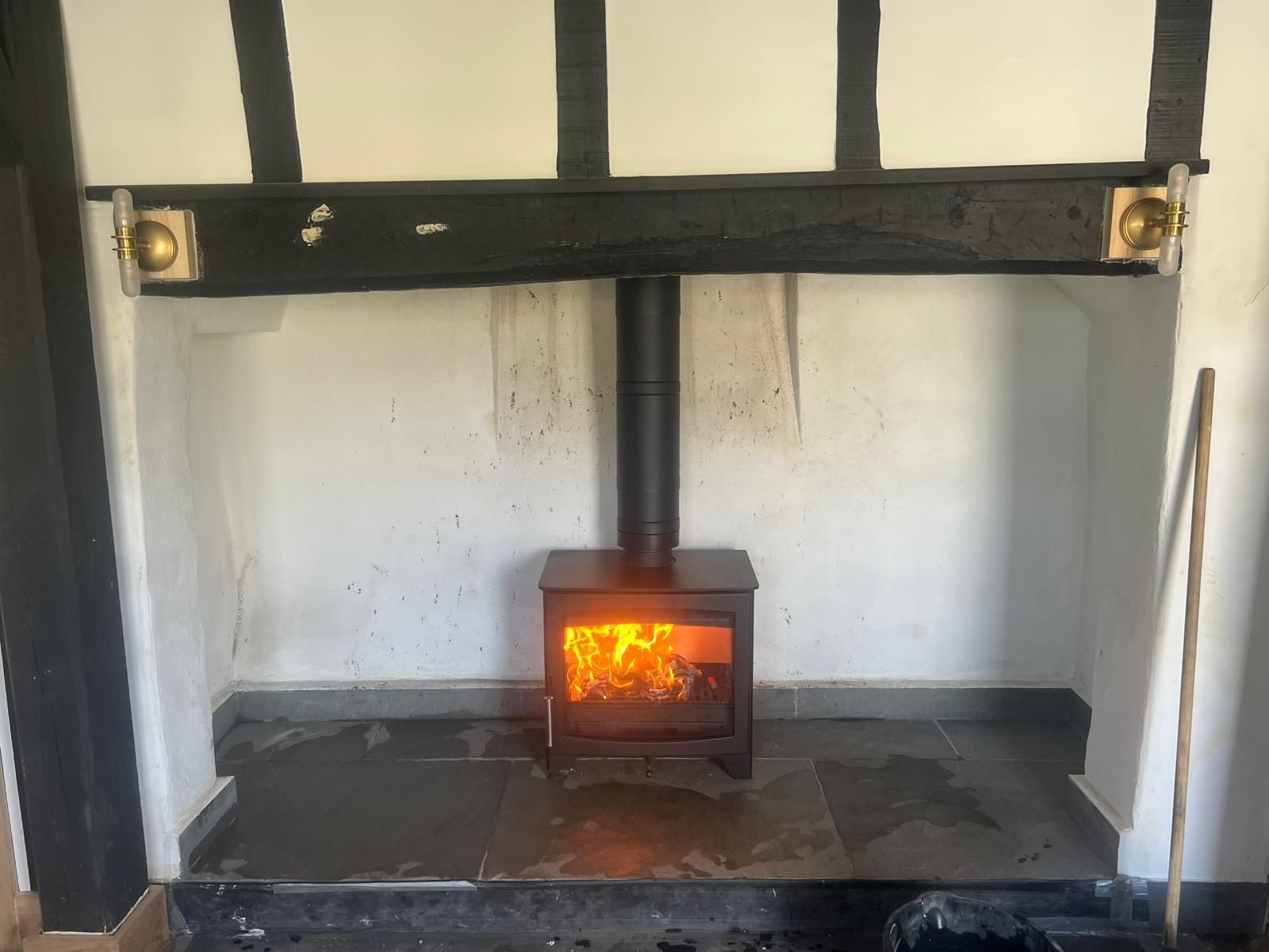 a traditional stove with a black frame, situated in a cozy fireplace setup