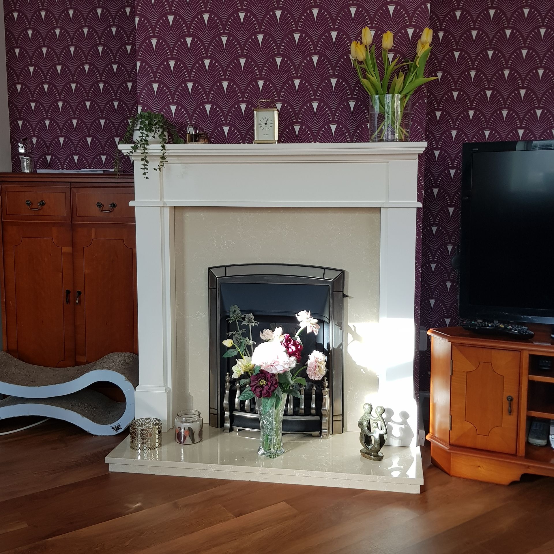 Classic fireplace with white mantel, floral decor, and patterned wall background