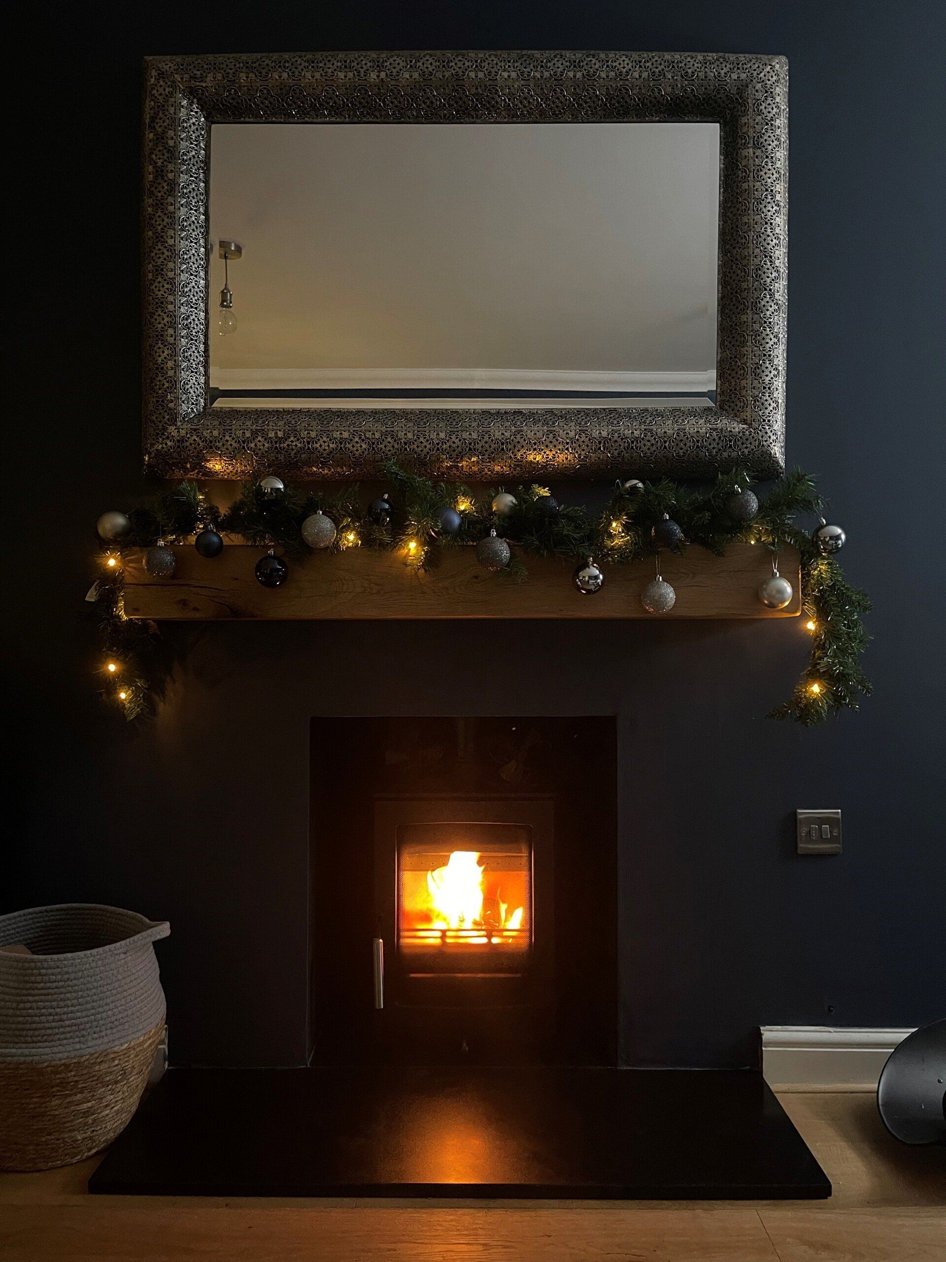 Wood burning stove with festive garland and mirror in a dark cosy room