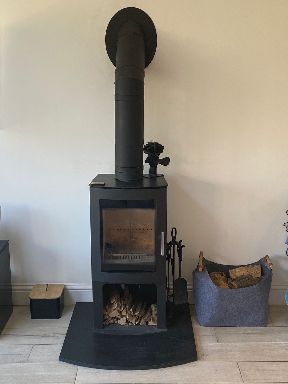 Wood burning stove in a simple plastered fireplace with wooden mantel