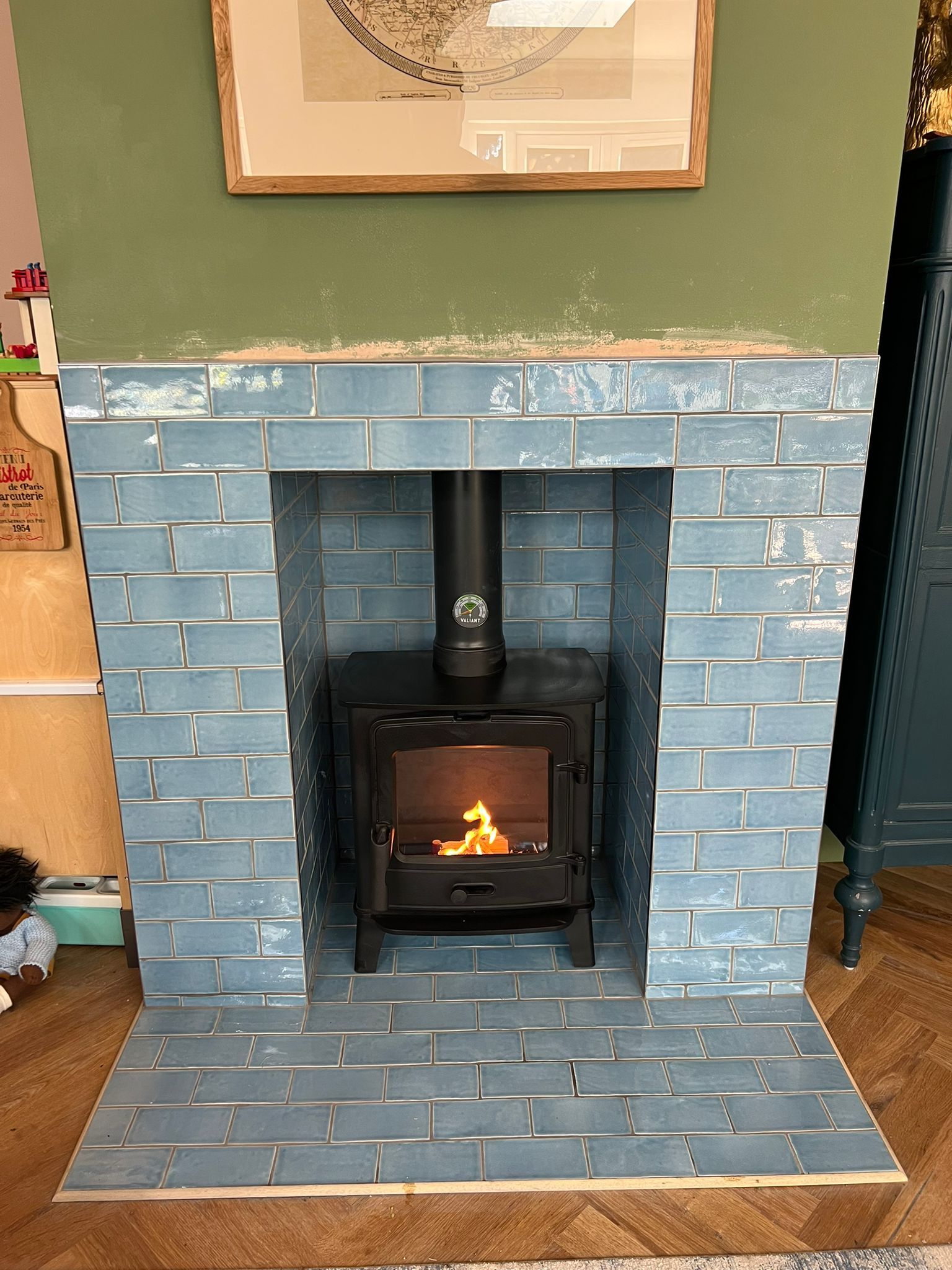 a cozy stove set in a fireplace with blue subway tiles
