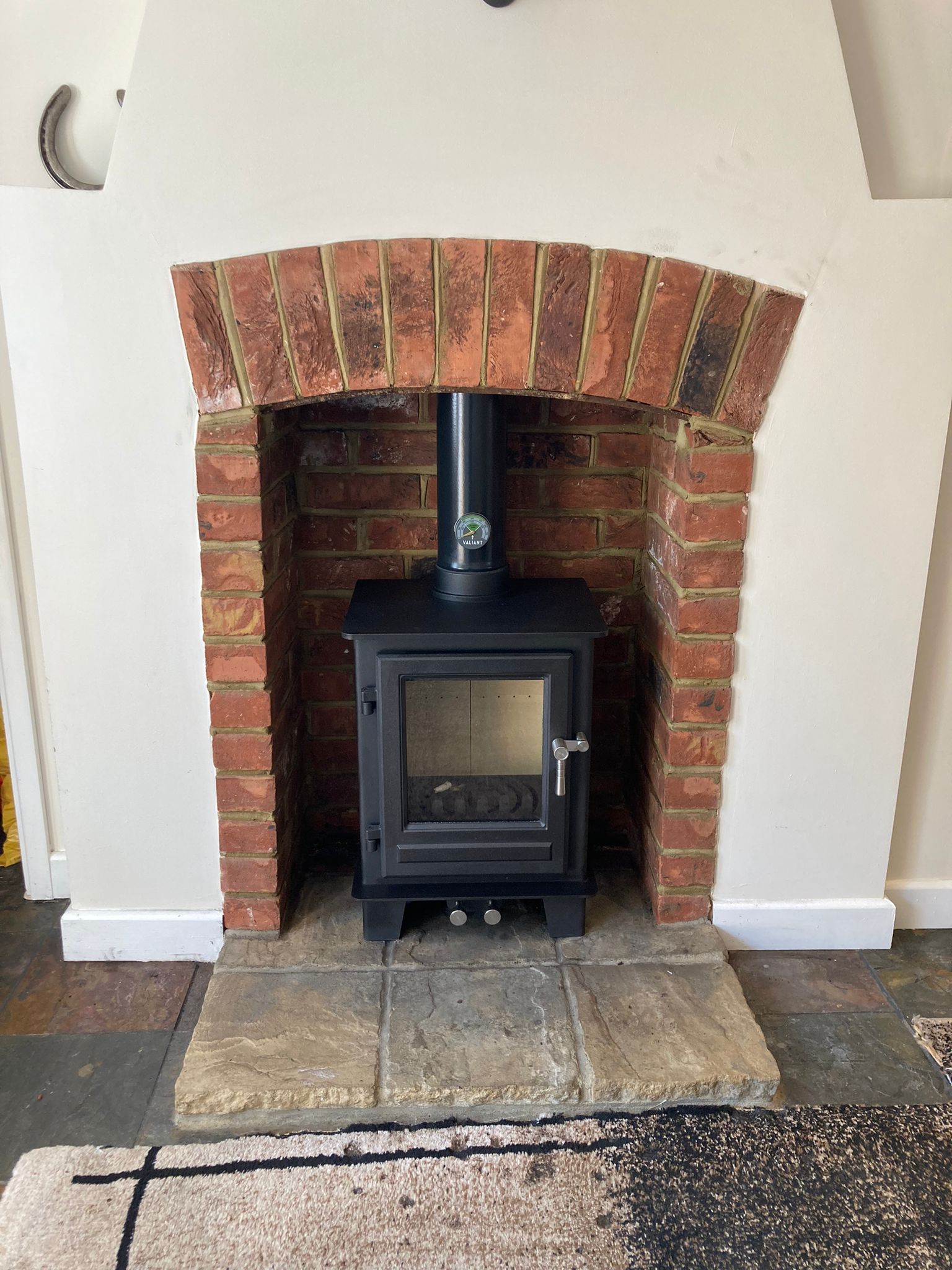 Wood burning stove set in a brick fireplace with arched opening and stone hearth