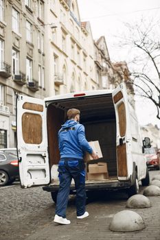 Un trabajador carga cajas en una furgoneta de reparto blanca en una calle de la ciudad.