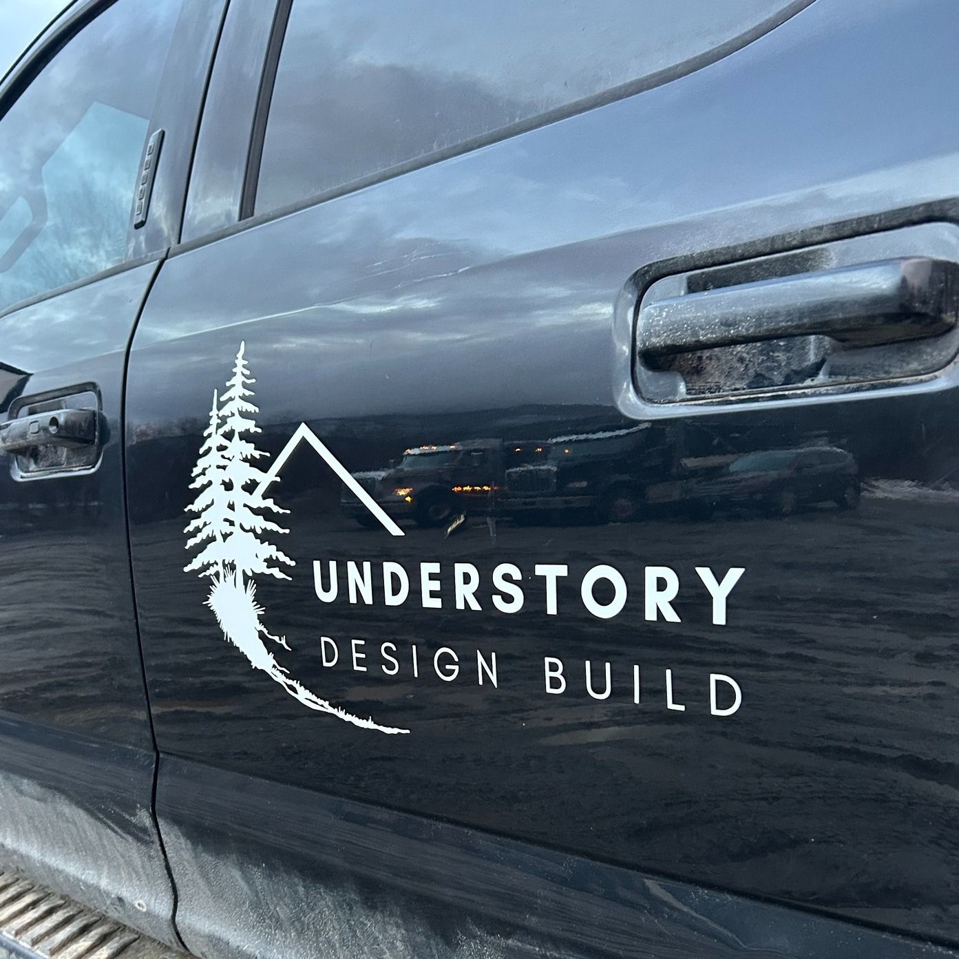 Black truck door with "Understory Design Build" logo featuring a mountain and pine tree graphic.